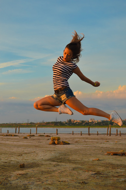 young pretty lady having fun jumping high over outdoors background copy space - Photo, Image