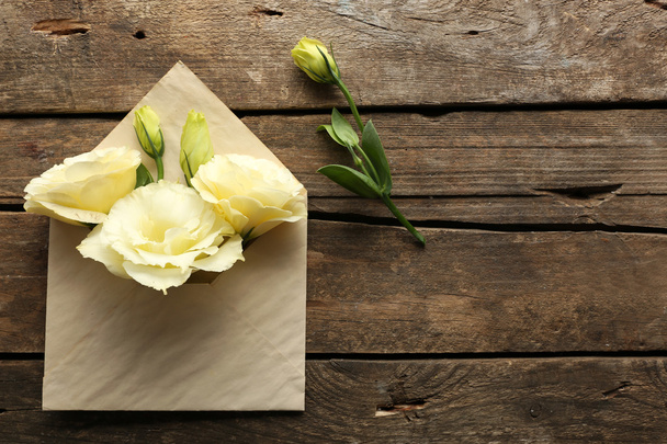 White eustoma in envelope on wooden background - Foto, afbeelding