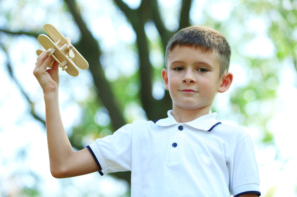 Little boy plays with wooden plane  - Valokuva, kuva
