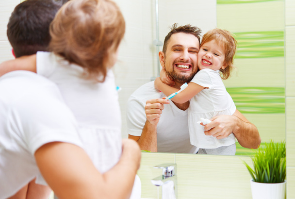 Happy family father and child girl brushing her teeth in bathroo - Fotoğraf, Görsel