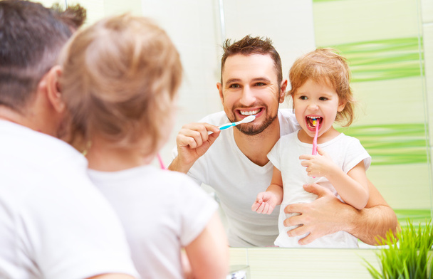 Happy family father and child girl brushing her teeth in bathroo - Photo, Image