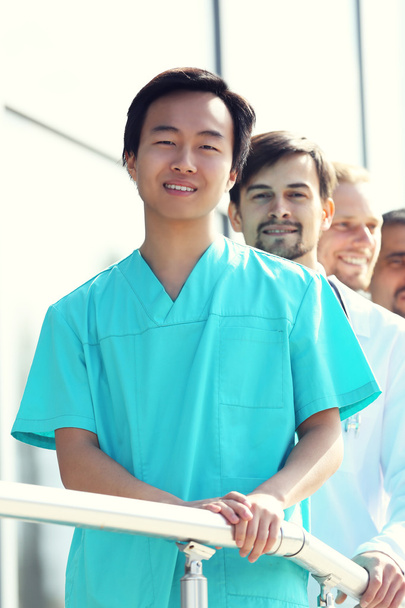Όμορφος χαμογελώντας γιατροί στέκονται σε μια σειρά κοντά στην κλινική - Φωτογραφία, εικόνα