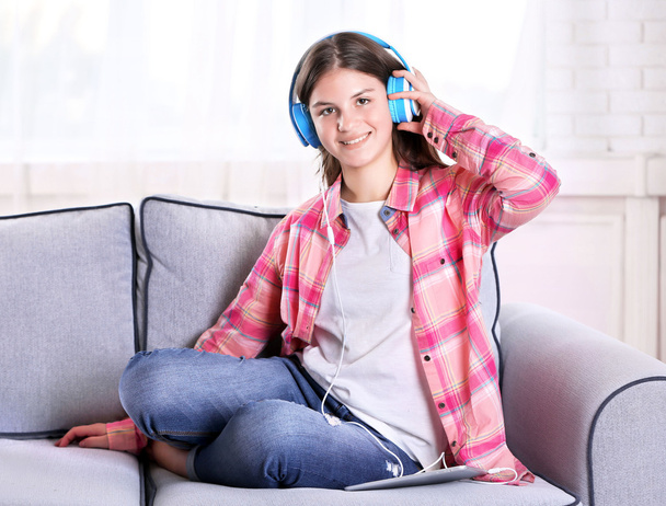 Linda chica escuchando música en el sofá
  - Foto, imagen