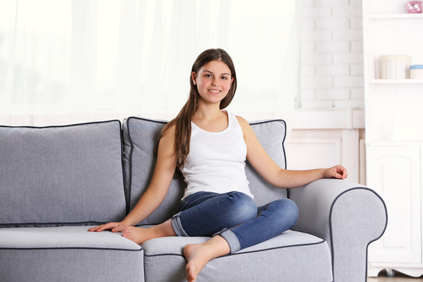 young pretty girl sitting on sofa  - Фото, изображение