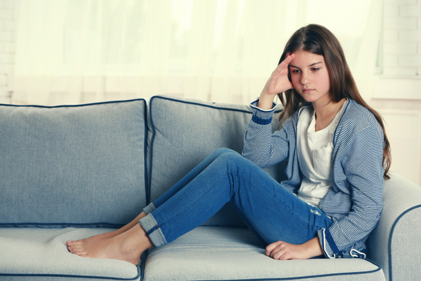 Расстроенная девушка сидит на диване
  - Фото, изображение