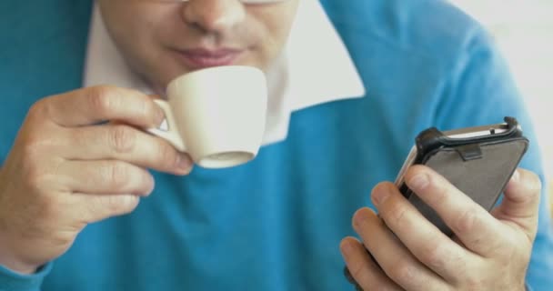 Erwachsener Mann benutzt Smartphone und trinkt Kaffee - Filmmaterial, Video