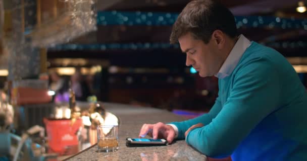Młody człowiek pisze smsy na komórce w barze - Materiał filmowy, wideo
