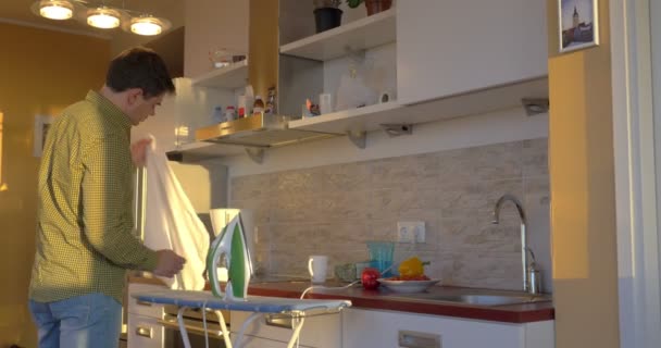 Erwachsener Mann bügelt weißes Hemd in der Küche - Filmmaterial, Video