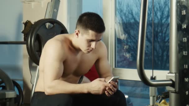 Der Bodybuilder schaut ins Telefon - Filmmaterial, Video
