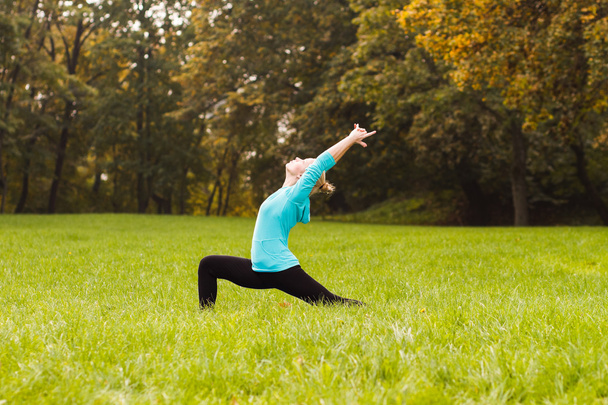 Woman practicing yoga in park - Foto, Bild