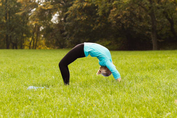 Woman practicing yoga in park - Foto, imagen