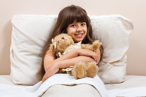 κορίτσι στο κρεβάτι με αρκούδα παιχνίδι - Φωτογραφία, εικόνα