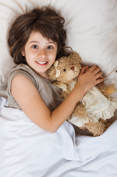 girl in bed with bear toy - Foto, afbeelding