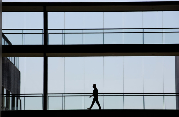 Вид силуету молодого бізнесмена, що йде в сучасному офісному будинку
 - Фото, зображення