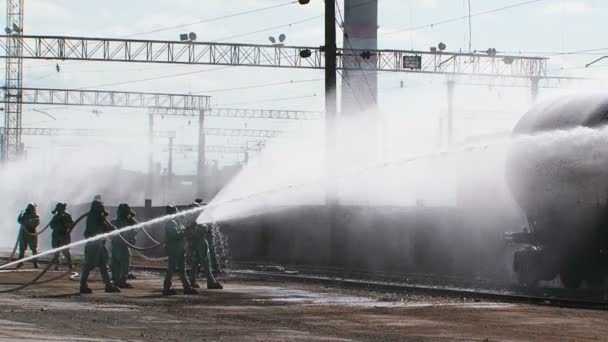 Gruppe von Feuerwehrleuten gießt Tank am Bahnhof - Filmmaterial, Video