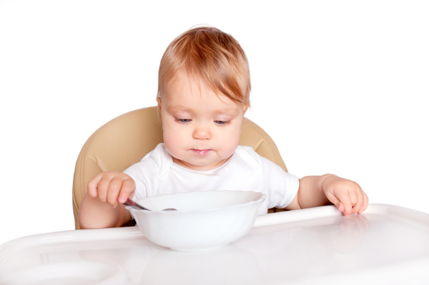 Bebé comiendo con cuchara en silla alta
 - Foto, Imagen