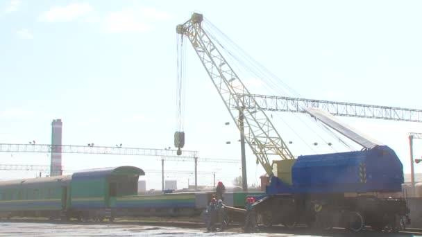 Železniční dělníci nakládací vůz s velkým jeřábem na stanici - Záběry, video