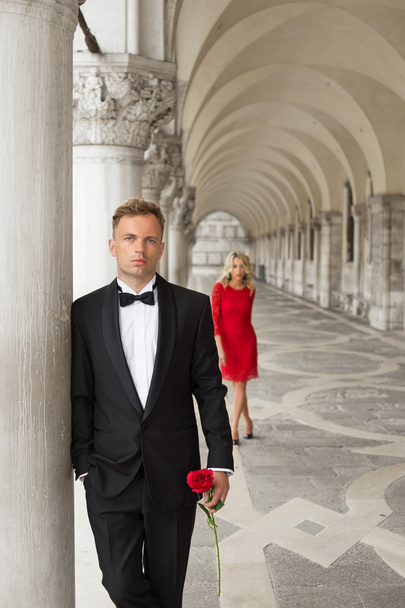 elegant gekleideter Mann hält Rose in der Hand und wartet auf sein Date - Foto, Bild