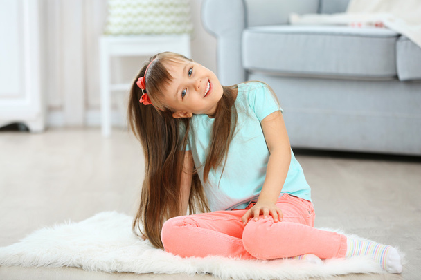 Little cute girl sitting on carpet - Foto, Imagen