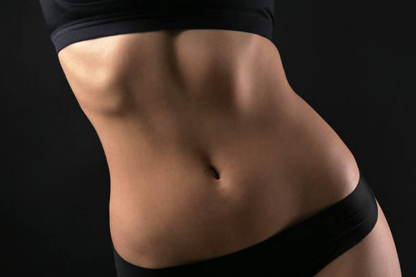 Slim female body in nice black lingerie on dark background - Foto, Imagen
