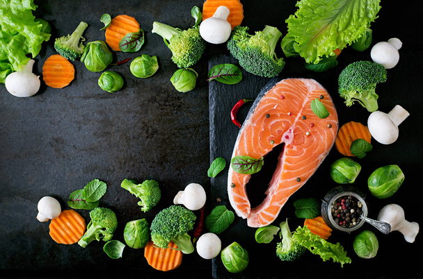 Raw salmon steak and ingredients for cooking on a dark background in a rustic style. Top view - Photo, Image
