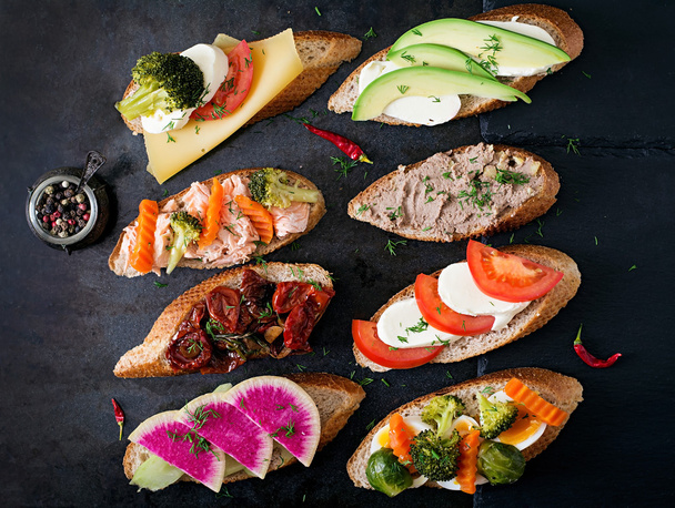 Різноманітність здорових бутербродів на темному тлі в сільському стилі. Вид зверху
 - Фото, зображення