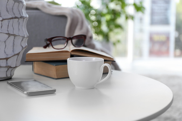 Taza de café con libros en la mesa en la habitación
 - Foto, imagen