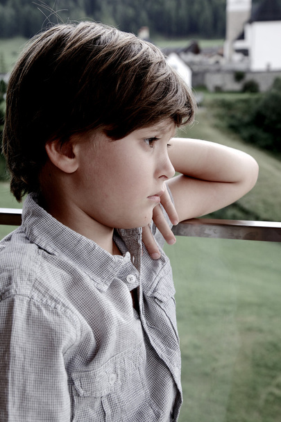 Smutny chłopiec zamyślony przed górami zbliżenie - Zdjęcie, obraz