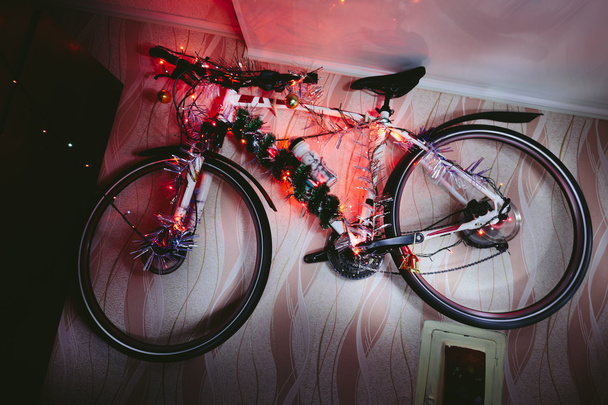 Bicycle on a wall decoration of the christmas lamp garland. - 写真・画像