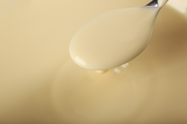 Fond de lait condensé et une cuillère dans un bol, gros plan
 - Photo, image