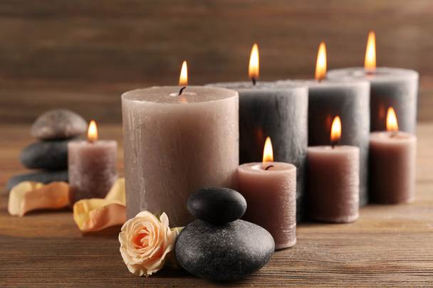 Alight wax grey candles with roses on wooden background - Foto, immagini
