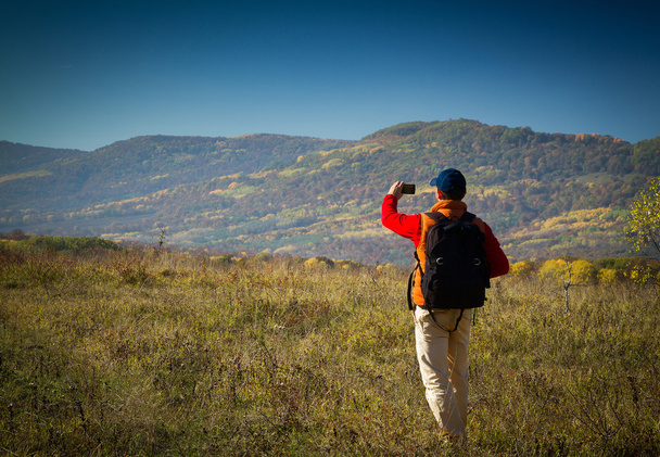 Touriste masculin avec sac à dos prenant des photos de paysages à votre s
 - Photo, image