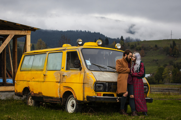 Pareja enamorada cerca de coche amarillo en las montañas Karpathian
 - Foto, Imagen