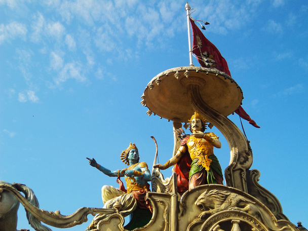 Lordi Krishna saarnaa Bhagavadgitaa Arjunalle Kurukshetran taistelukentällä.
 - Valokuva, kuva