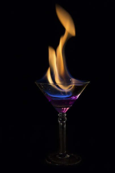 Martini-Glas mit lila Getränk brennt und ist sehr heiß - Foto, Bild