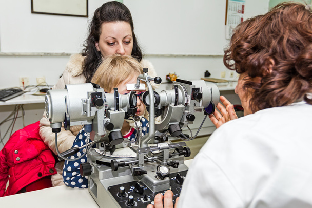 Optometrist with patient, giving an eye examination - Foto, afbeelding