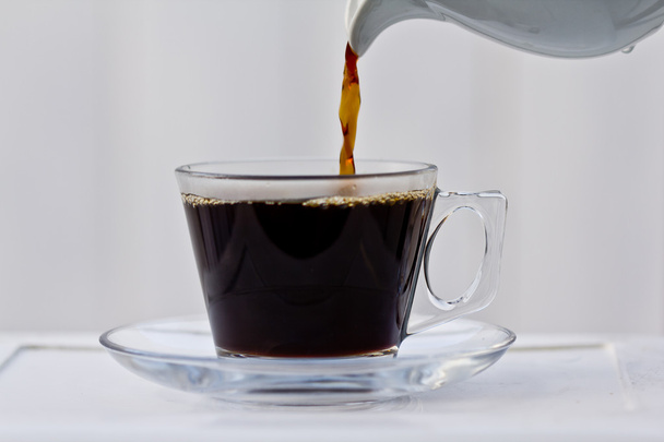 Pouring coffee into an almost full cup - Фото, изображение