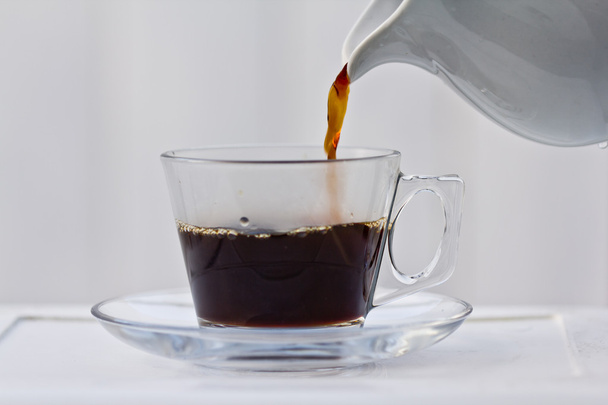 Pouring coffee into a half full cup - Фото, изображение