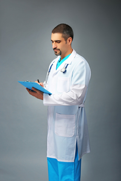 Portrait of a doctor with prescription board in hands  on grey background - Фото, изображение