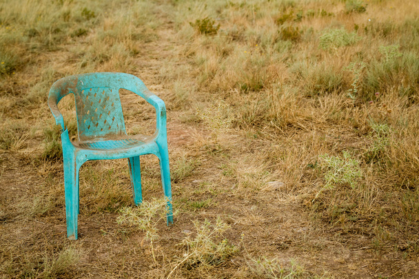 Grungy retro vaurioitunut muovi vihreä tuoli hylätty pellolla
 - Valokuva, kuva