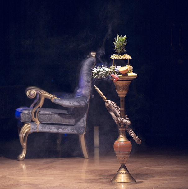 Exotic hookah. Different hookah over the bright backgrounds with smoke. Hookah with fruit flavour on wooden table in vintage style - Photo, Image