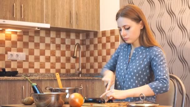 Terveellinen ruoka elämäntapa: kaunis nainen rennosti ruoanlaitto, leikkaamalla vihanneksia keittiössä. Keskikokoinen laukaus, käsikäyttöinen
. - Materiaali, video