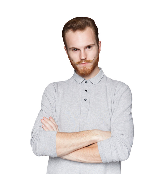 junger Mann mit Bart und Schnurrbart, die Arme auf weißem Hintergrund verschränkt - Foto, Bild