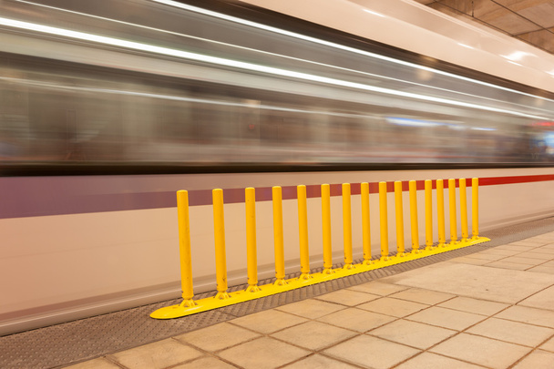 Желтый барьер безопасности на платформе метро, как размытое изображение
  - Фото, изображение