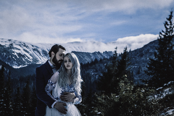 Lovely bride and groom in winter snow on mountain - Фото, изображение