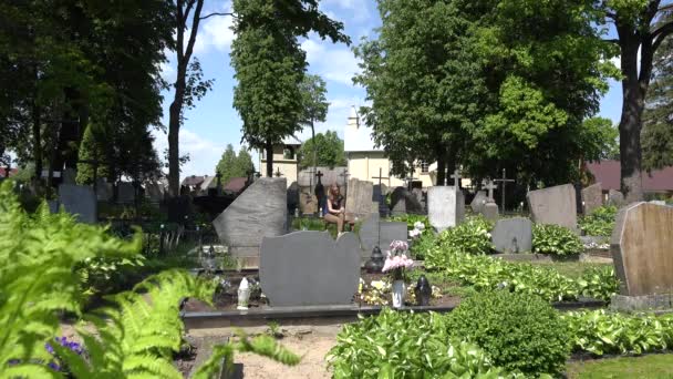 Trauernde Frauen schrumpfen neben dem Grab ihres Ehemannes auf dem Friedhof. 4k - Filmmaterial, Video