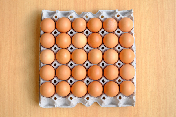 Une douzaine d'œufs bruns dans un carton sur une table en bois
 - Photo, image