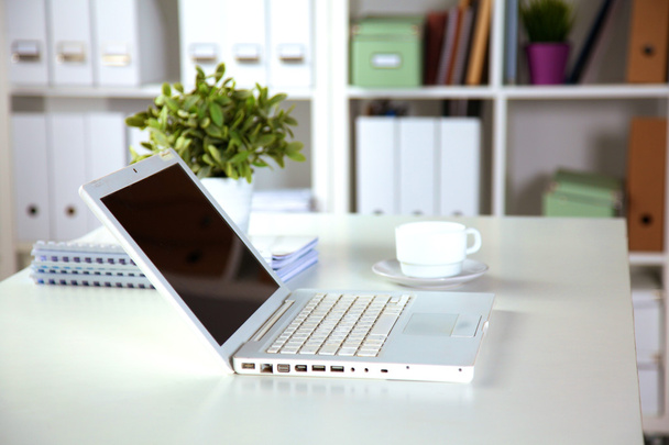 Vista da vicino di un interno scrivania con un computer portatile, una tazza di caffè e tende bianche in una giornata di sole
 - Foto, immagini