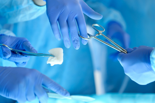 Χειρουργοί τα χέρια κρατώντας και περνώντας χειρουργικά μέσο σε άλλο  - Φωτογραφία, εικόνα