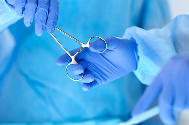 Хирурги держат руки и передают хирургический инструмент другим
  - Фото, изображение